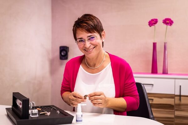 Hörakustikerin bei der Reinigung und Wartung von modernen Hörgeräten im Fachgeschäft.